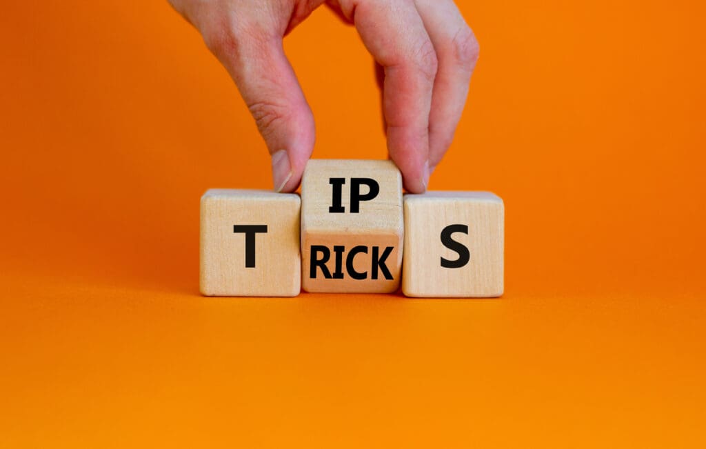 Tips and tricks symbol. Businessman turn the wooden cube and changes the word 'tips' on 'tricks'. Beautiful orange background. Business and tips and tricks concept, copy space. Tips and tricks symbol. Businessman turn the wooden cube and changes the word 'tips' on 'tricks'. Beautiful orange background. Business and tips and tricks concept, copy space.