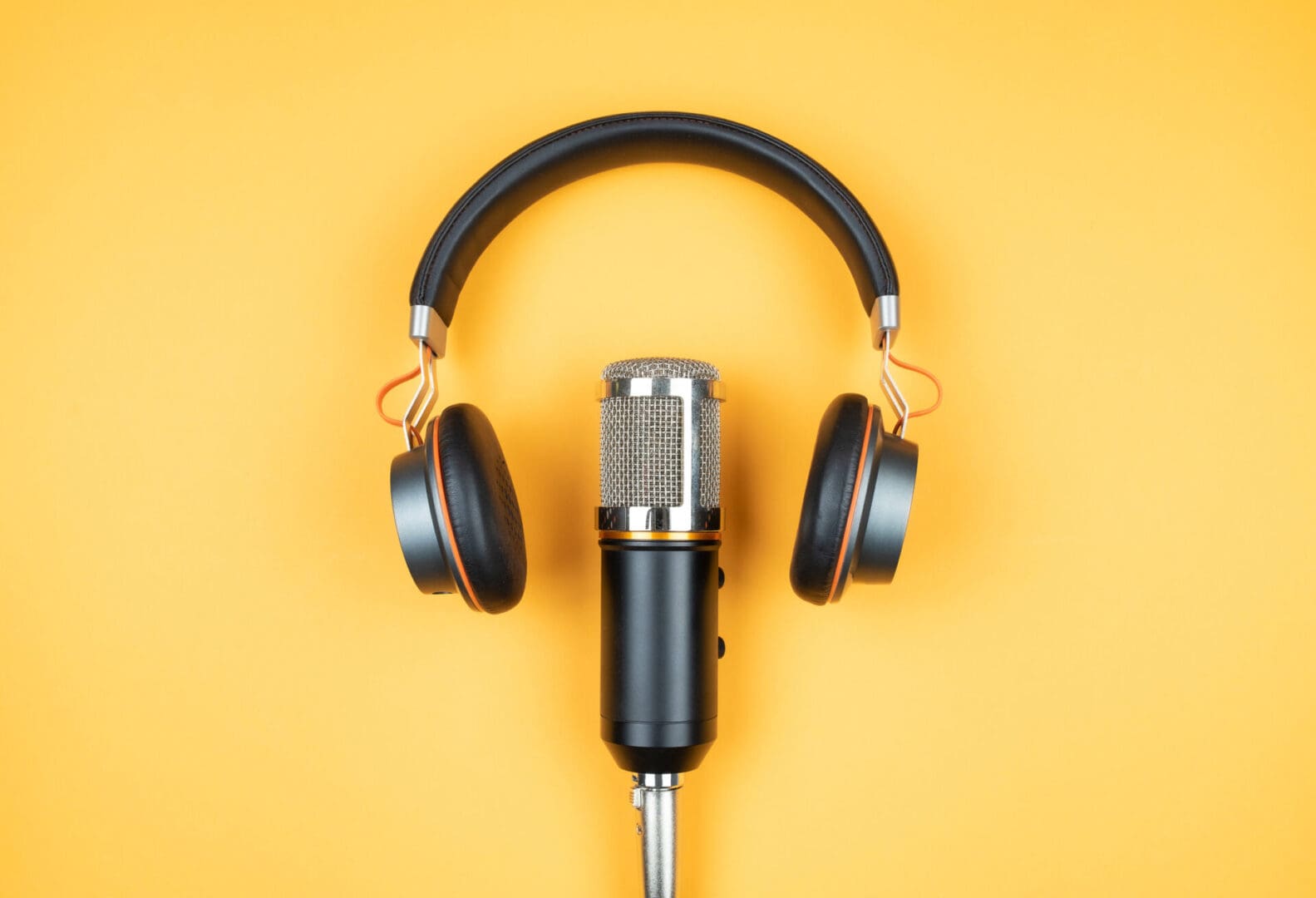 Microphone with headphones on a yellow background.