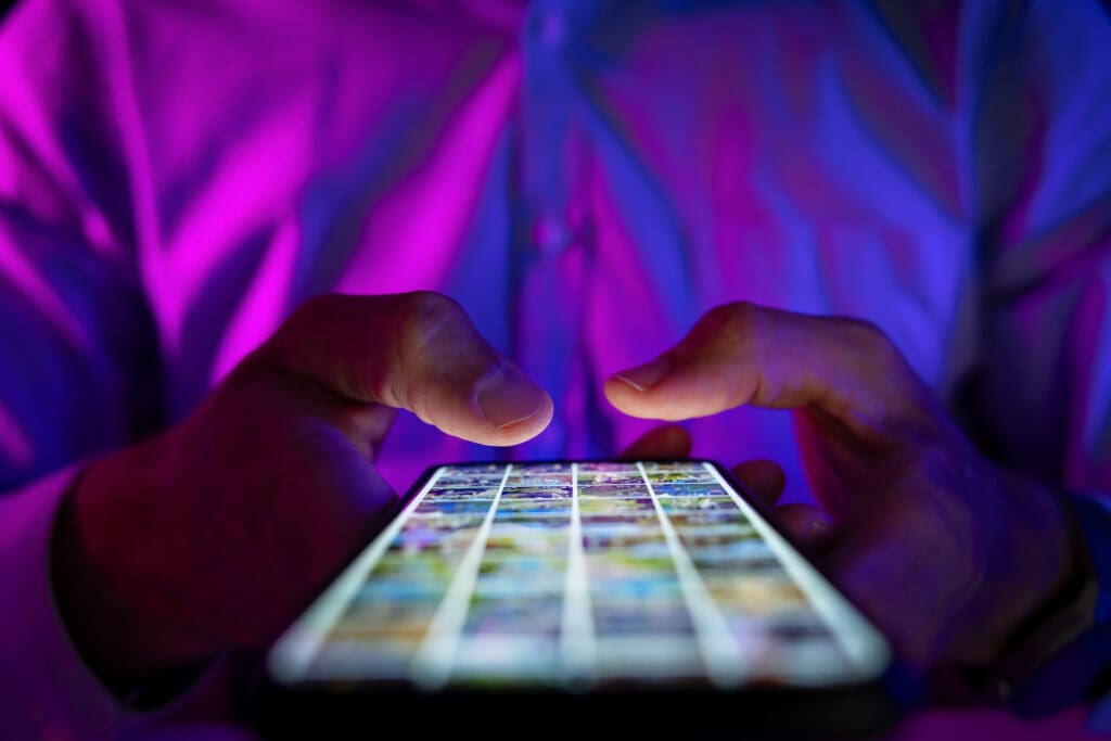 man scrolling mobile phone screen in dark room with neon lights. internet browsing, social media and marketing man scrolling mobile phone screen in dark room with neon lights. internet browsing, social media and marketing