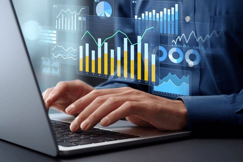 Hands typing on a laptop with digital financial charts overlay.